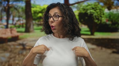 Orta yaşlı, gözlüklü ve yeşil parkta kendini gösteren İspanyol bir kadın..