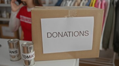 Bağış kutusu ve konserve kutusuyla yardım merkezinde telefonla konuşan bir kadın..