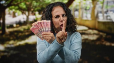 Orta yaşlı bir kadın parkın dışında, elinde Güney Afrika banknotları tutuyordu. Sinirli bir şekilde parmaklarıyla hareket ediyordu. Doğal bir bahçe ortamında anlaşmazlıklarını dile getiriyordu..