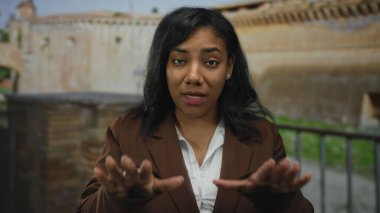 Kadın, eski şehir caddesinde durmak için avuçlarını ileri uzatıyor. Ciddi bakışlarla taş bina cephesine bakıyor..