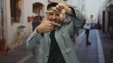 Genç İspanyol asıllı bir adam, şehir sokaklarında hareketli bir el hareketleriyle fotoğraf sanatında yaratıcılığını ve hareketliliğini gösteriyor..