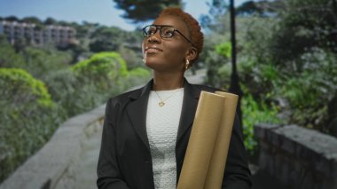 Elinde planlar olan kadın mimar, parlak güneş ışığı altında yemyeşil bir ormanda taş kaldırım boyunca yukarı bakıyor. Profesyonel hırs..