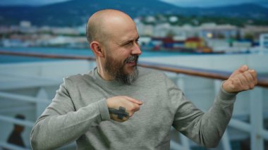 Teknede sakallı bir adam deniz kenarında görünmez bir halat çekiyor..