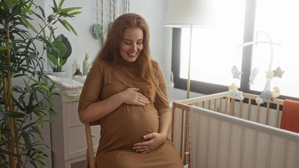 Hamile kadın, bebek odasındaki ahşap bir karyolanın yanında çıplak karnını tutuyor..