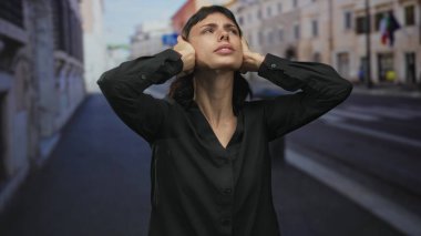 Siyah gömlekli kadın el ele tutuşup tarihi caddeye doğru bakıyor. İç huzursuzluk iç huzursuzluğu korkutuyor..