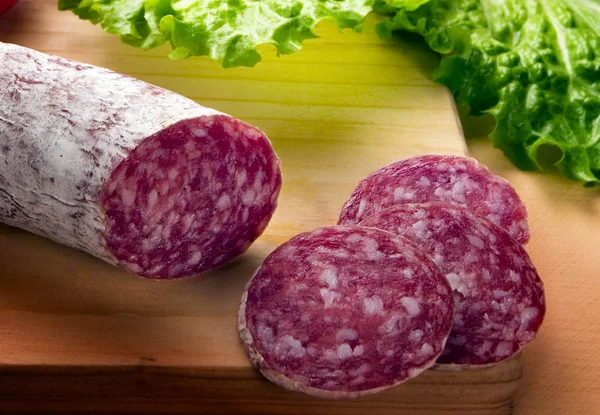 üç dilim salam, domuz eti, yeşil yaprakları ile ahşap tablo