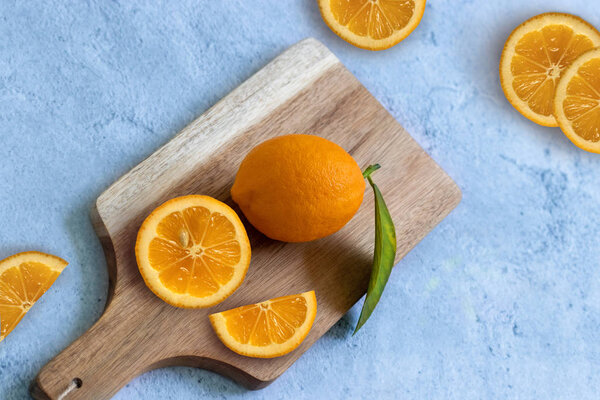 Lemons and oranges wooden chopping board on blue background