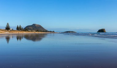 Gün doğumunda, Yeni Zelanda sahilde bir grup insan silueti. 
