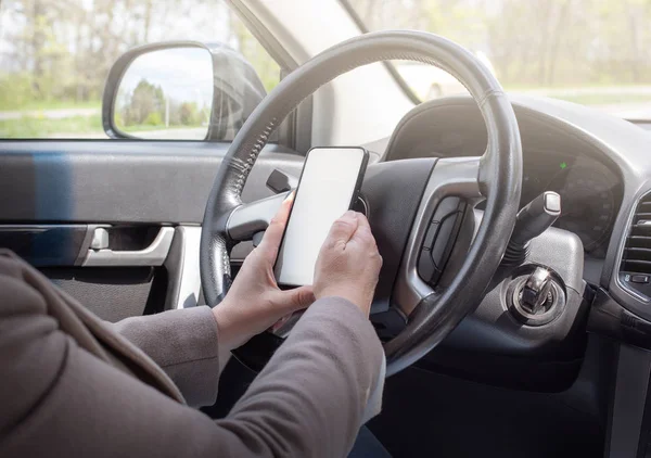 Young female driver using touch screen smartphone — Stock Photo, Image
