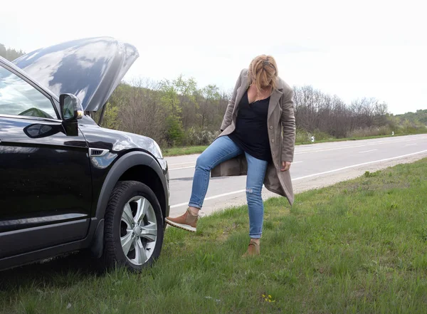 stock image Blonde woman and broken down car on road 