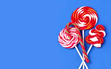 Mavi arka planda renkli lolipop. Düz yatıyordu. Asgari konsept