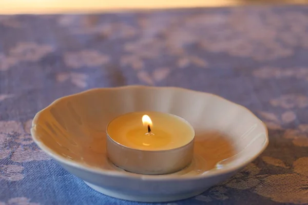 Kleine Kerze brennt in Untertasse auf dem Tisch — Stockfoto