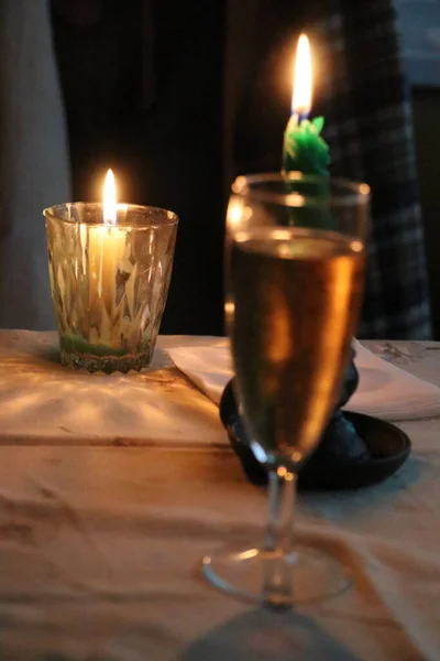 Una copa de champán y dos velas en el fondo — Foto de Stock
