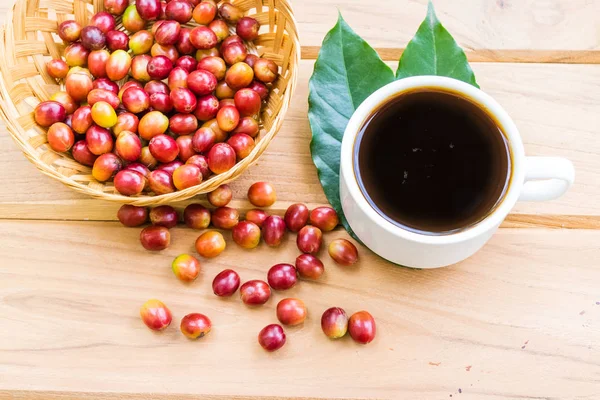A cup of coffee and red ripe coffee beans on a wooden stick