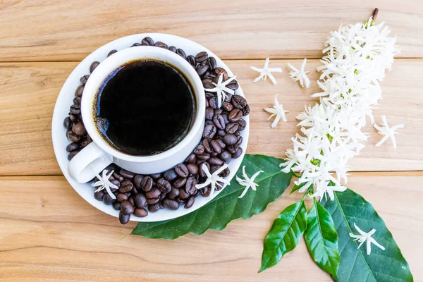 Coffee beans, Coffee flowers and a cup of coffee on the wood.