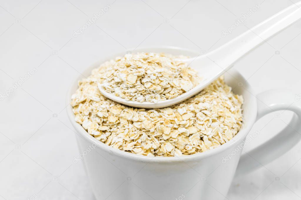 Oat flakes in white cup isolated on white background. Healthy food.