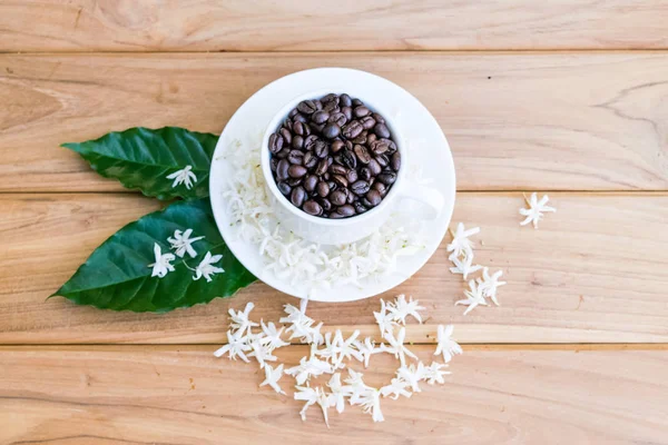 Coffee beans, Coffee flowers and a cup of coffee on the wood.