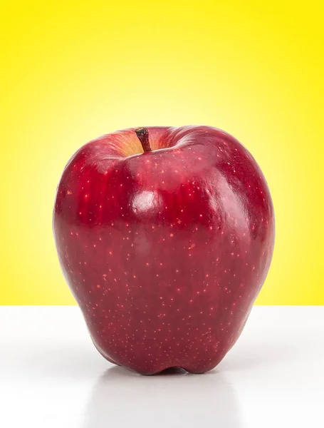 Lesklé červené jablko na žlutém pozadí — Stock fotografie