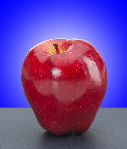 Lesklé červené jablko na modrém pozadí — Stock fotografie