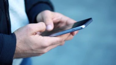 Yakın çekim görünümü, adam kullanma Smartphone şehrin sokak. 