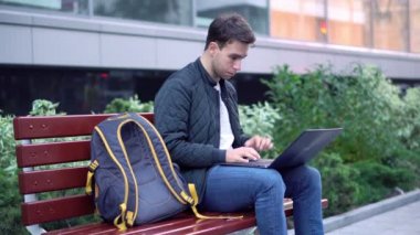 Şehrin sokak dizüstü bilgisayar üzerinde çalışan genç çekici öğrenci