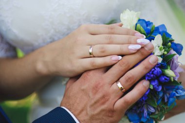 Yeni evlilerin elleri düğün buketinde.