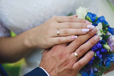 Yeni evlilerin elleri düğün buketinde.