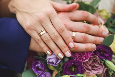 Yeni evlilerin elleri düğün buketinde.