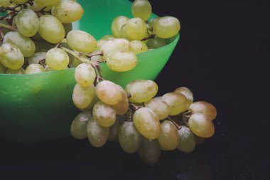 karanlık bir arka plan üzerine bir tabak içinde üzüm demet