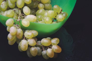 karanlık bir arka plan üzerine bir tabak içinde üzüm demet