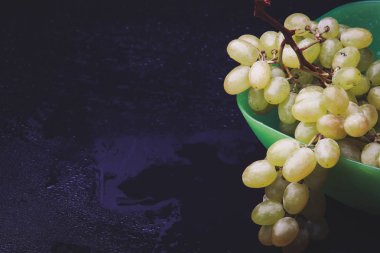 karanlık bir arka plan üzerine bir tabak içinde üzüm demet
