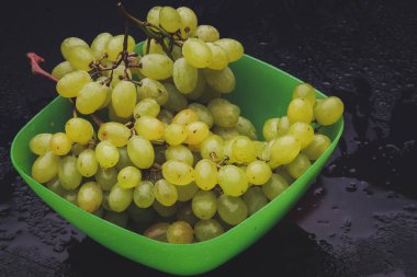 karanlık bir arka plan üzerine bir tabak içinde üzüm demet