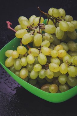 karanlık bir arka plan üzerine bir tabak içinde üzüm demet