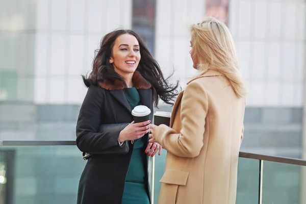 two women walk in the city, drink coffee and enjoy the rest