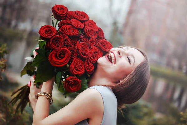 公園に花の大きな花束を持つ美しい若い女性 — ストック写真