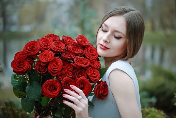 公園に花の大きな花束を持つ美しい若い女性 — ストック写真