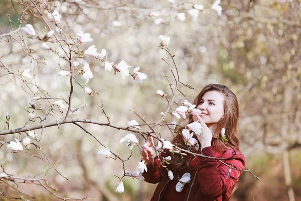 庭の開花木を嗅ぐ美しい若い女性 — ストック写真