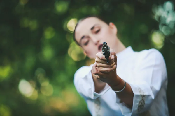 woman with a gun in a white embroidered dress on the street