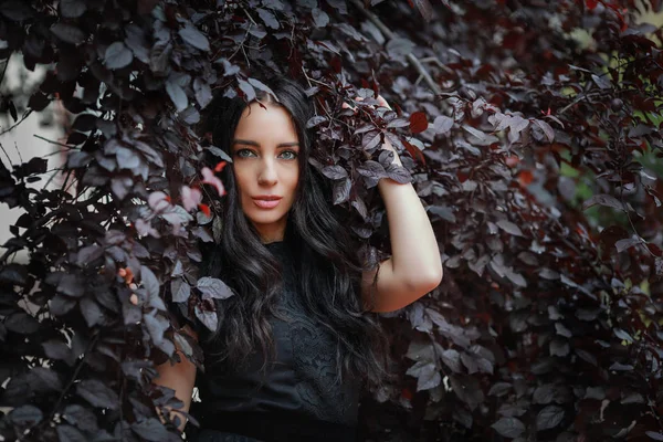美丽的女人在花园里的叶子黑衣服 — 图库照片