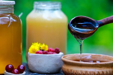 bir seramik kase içinde ahşap kaşık damlayan taze tatlı bal