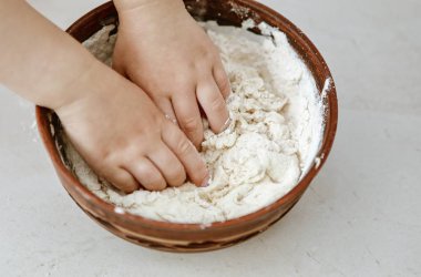 bebek elleri bir pizza tabağı içinde hamur yoğurun