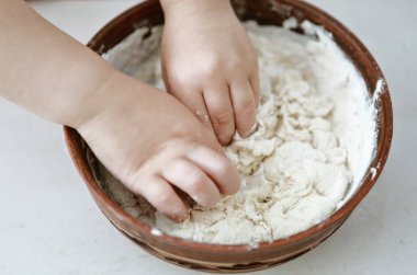 bebek elleri bir pizza tabağı içinde hamur yoğurun