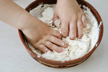 bebek elleri bir pizza tabağı içinde hamur yoğurun