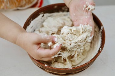 bebek elleri bir pizza tabağı içinde hamur yoğurun
