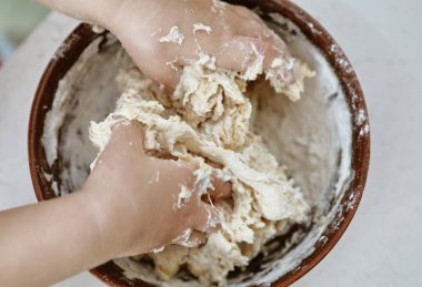 bebek elleri bir pizza tabağı içinde hamur yoğurun