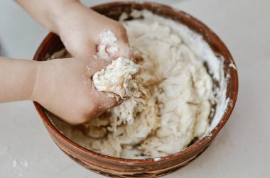 bebek elleri bir pizza tabağı içinde hamur yoğurun