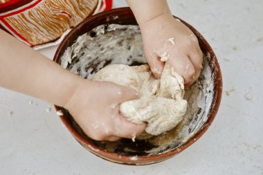 bebek elleri bir pizza tabağı içinde hamur yoğurun