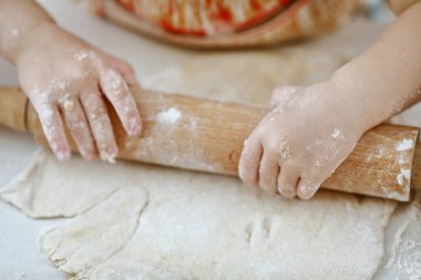 bebek elleri bir pizza tabağı içinde hamur yoğurun