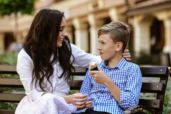 mother and son eat ice cream on the bench and have fun