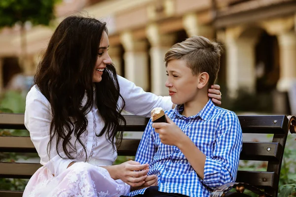 mother and son eat ice cream on the bench and have fun